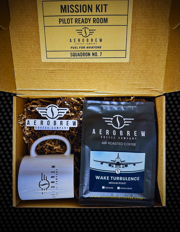 Aerosbrew coffee kit with coffee package, grinder, and packaging labeled 'Mission Kit' on a textured surface.